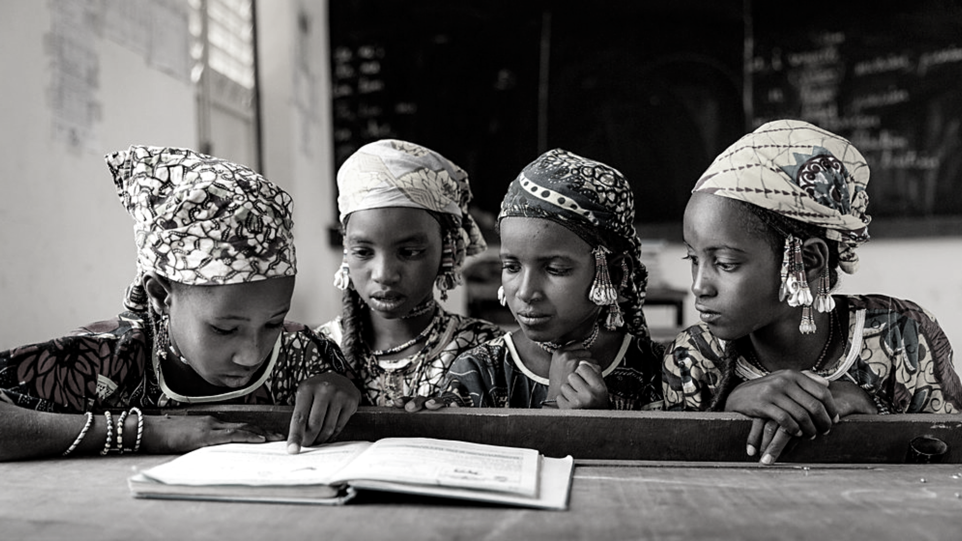 Young girls share a textbook in class. Ecole Patti, Makalondi, Tilaberri Region, Niger, 2017.
